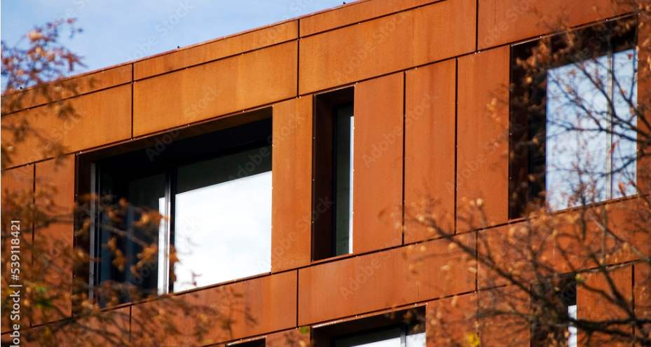 Édifice vu entre des arbres dont la façade est constituée de panneaux en composite aluminium larson® aspect Aciero Corten 